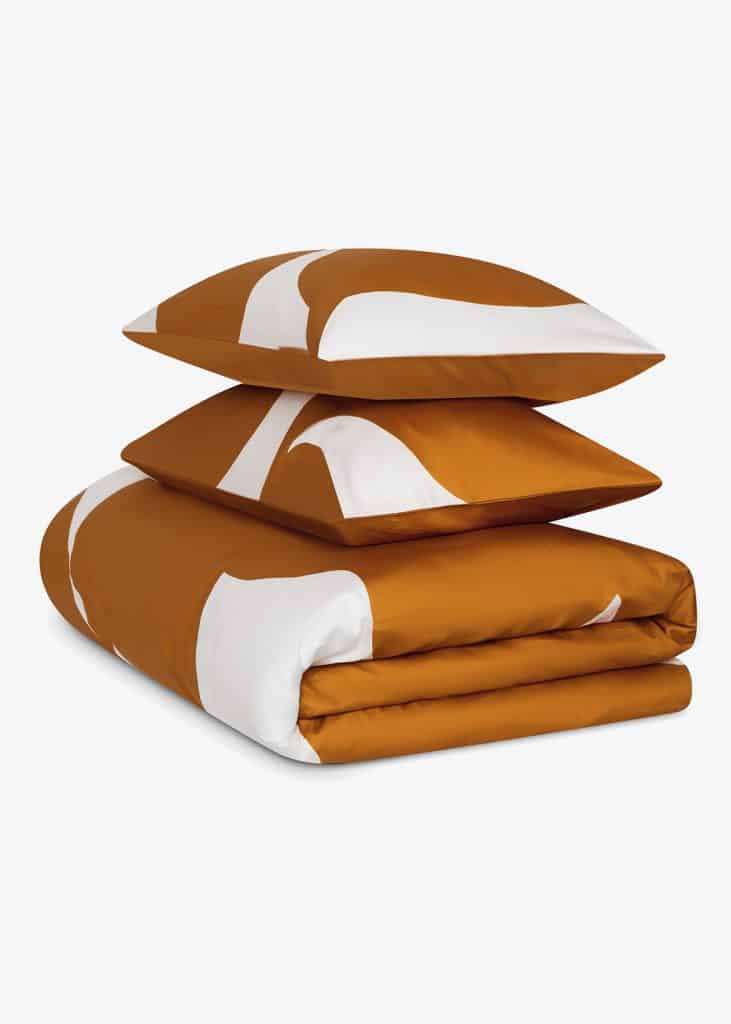 A stack of orange and white pillows designed by Jasper Conran London, a large item.